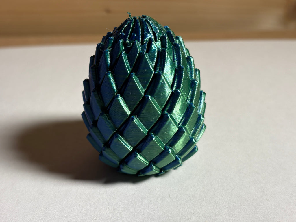 Green metallic dragon egg model on a neutral background