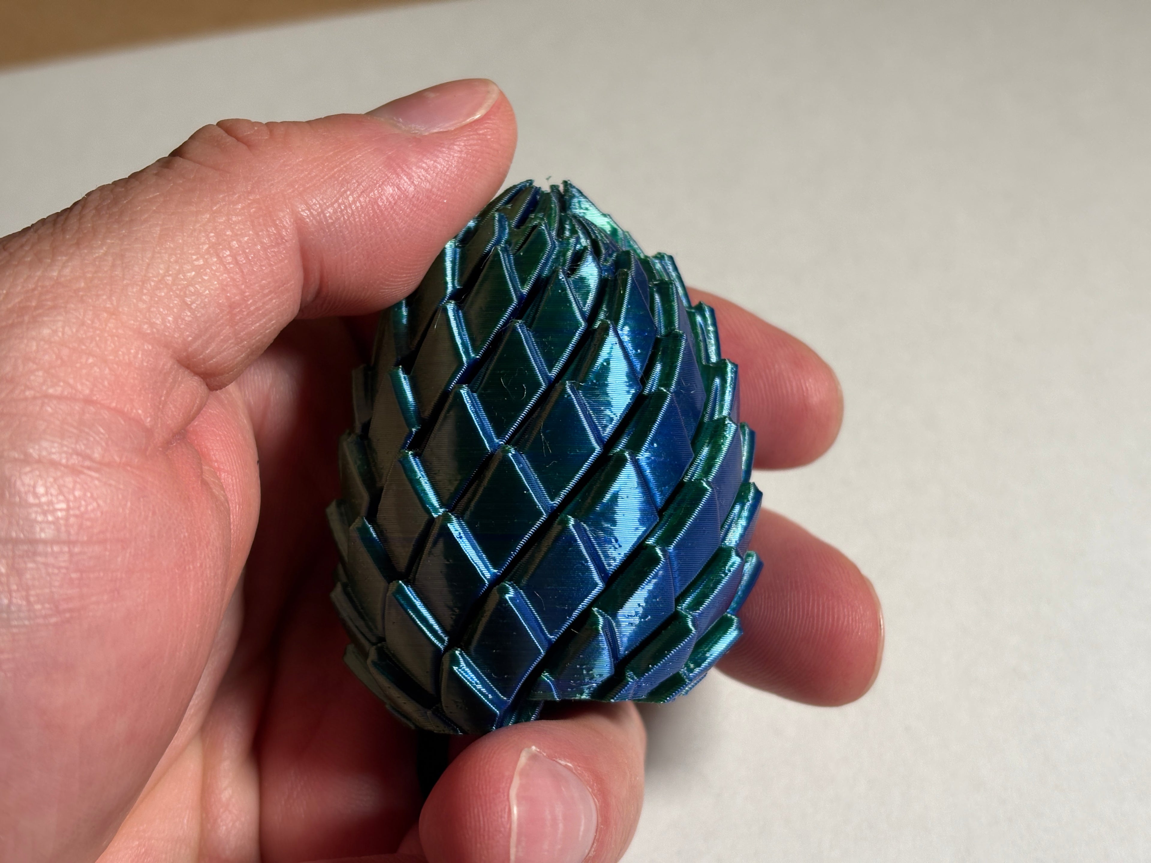 A hand holding a 3d printed dragon egg fidget toy