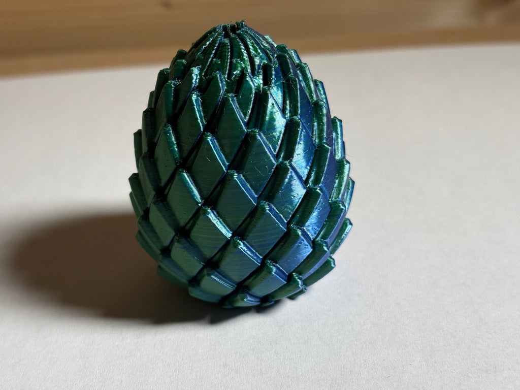 A 3d printed dragon egg fidget toy on a white desk