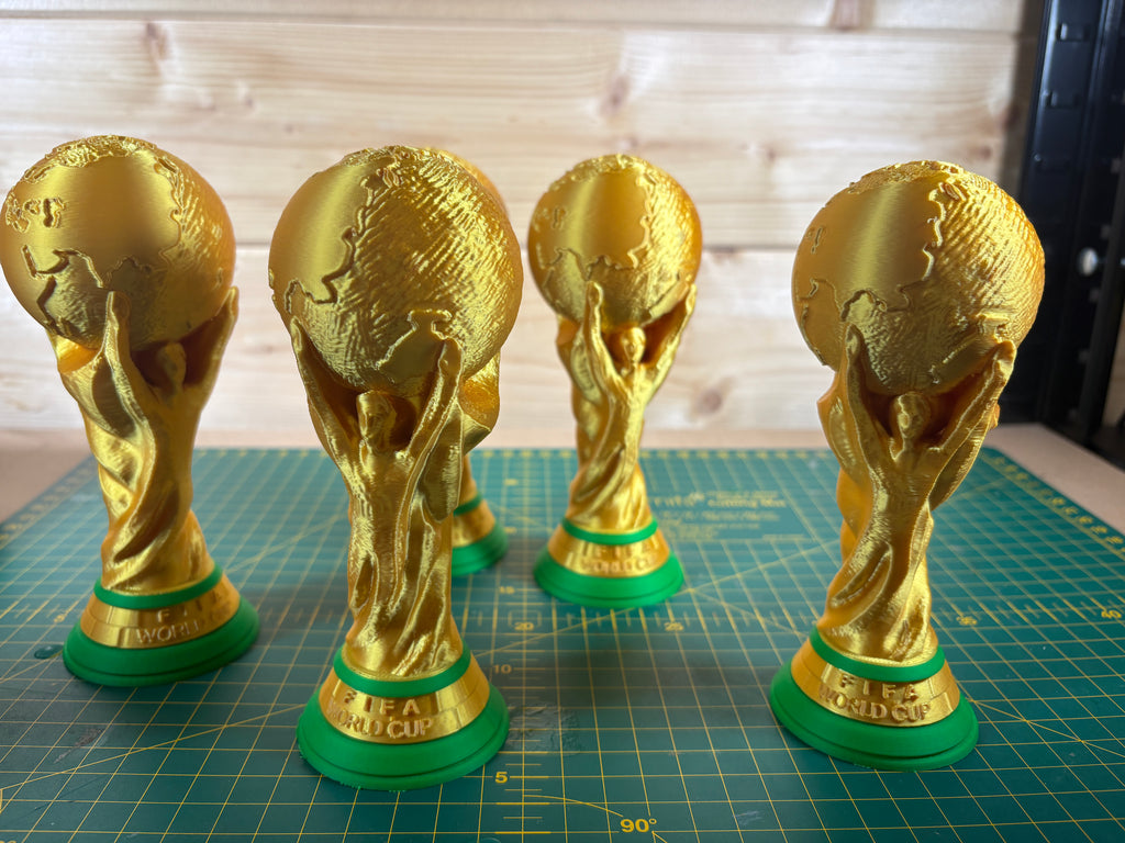 Gold World Cup trophies on a green cutting mat